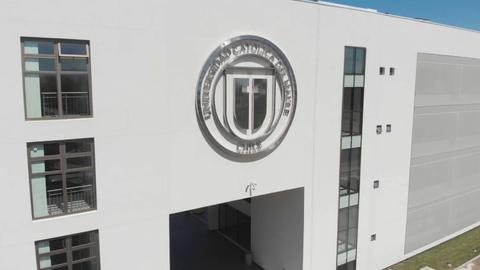 Edificio moderno de una universidad con el logotipo en la parte frontal.