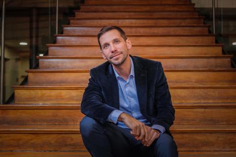 Un hombre sentado en una escalera de madera con una expresión pensativa.