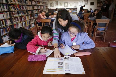 Un grupo de estudiantes está trabajando en una biblioteca, concentradas en sus tareas y estudios.