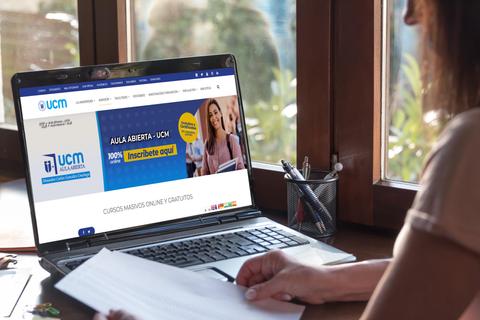 Una persona trabajando en un ordenador portátil mientras revisa documentos en un entorno luminoso.