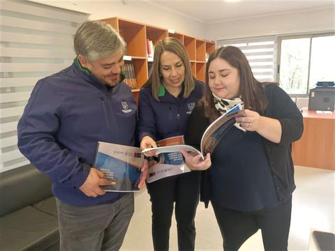 Tres personas revisan documentos en una oficina.
