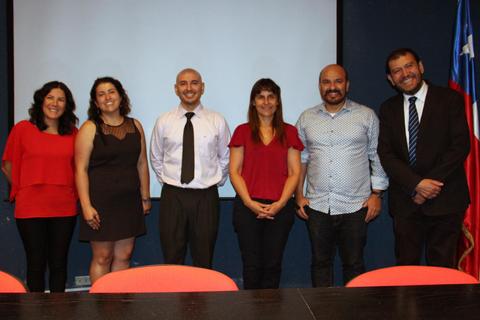 Un grupo de seis personas posando frente a una pantalla en un ambiente formal.