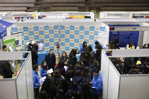 Una feria con estudiantes interactuando en una exposición educativa.