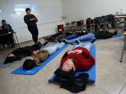 Un grupo de personas está realizando ejercicios de relajación en un salón de clases.