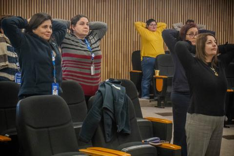 Mujeres participando en una sesión de ejercicios en una sala de conferencias.
