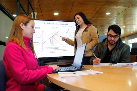 Un grupo de tres personas discutiendo sobre un modelo de precios de activos en una sala de clases.
