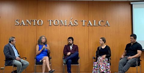 Una mesa redonda en la que cinco personas participan en una discusión en un auditorio.