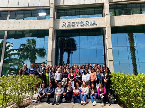 Un grupo grande de personas posa frente a un edificio con la palabra 'RECTORIA' en la fachada.