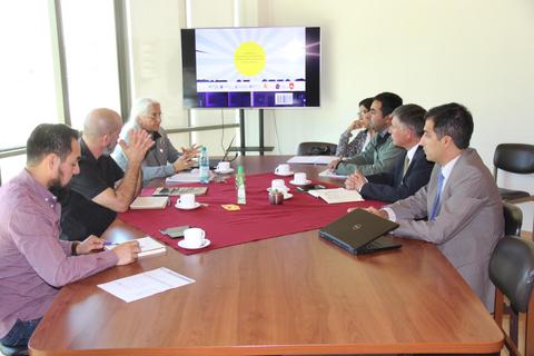 Reunión de un grupo de personas alrededor de una mesa con un proyector en el fondo.