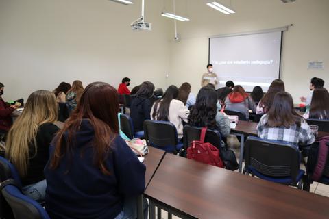 Una clase en un aula con estudiantes atentos a la presentación de un profesor.