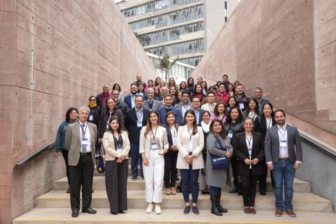 Un grupo grande de personas posando en escaleras de un edificio moderno.