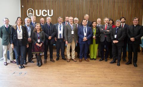 Un grupo de personas de pie en un evento formal en un salón con decoración moderna.