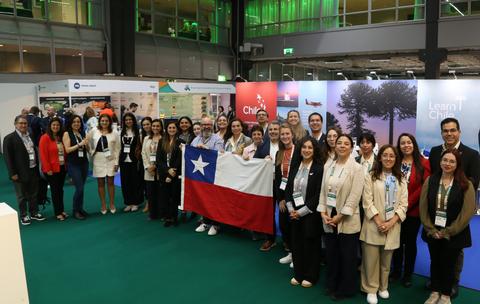 Una agrupación de personas posando en un evento con una bandera chilena.