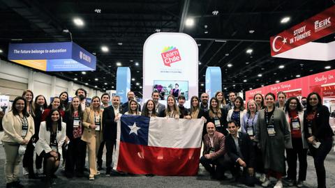 Un grupo de personas posando con una bandera chilena en un evento.