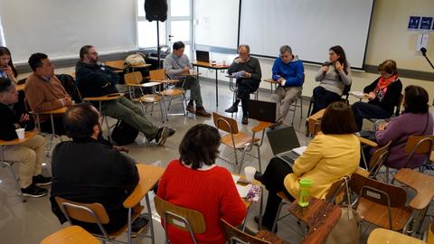 Una reunión en un aula con varias personas sentadas en sillas mientras discuten.