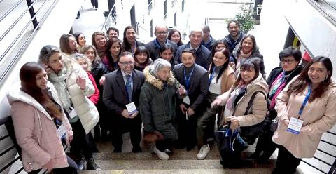 Un grupo diverso de personas se reúne en una escalera, sonriendo y posando para la foto.