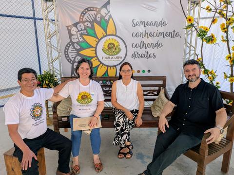 Cuatro personas sonrientes sentadas en un banquillo, compartiendo un mensaje positivo sobre el conocimiento y los derechos.