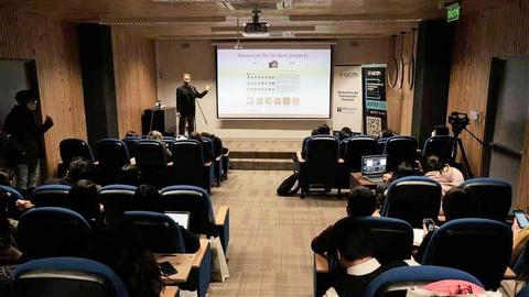 Un profesor está dando una presentación frente a un grupo de estudiantes en un aula.