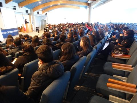 Una multitud de personas sentadas en un auditorio escuchando a un conferencista.