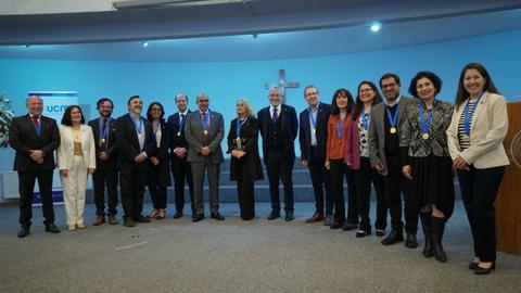 Un grupo de personas posando en un evento formal con medallas en un ambiente de celebración.