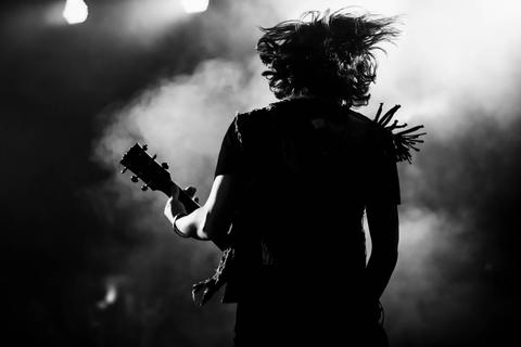 Un guitarrista en un concierto eléctrico, con su cabello volando enérgicamente sobre el escenario.