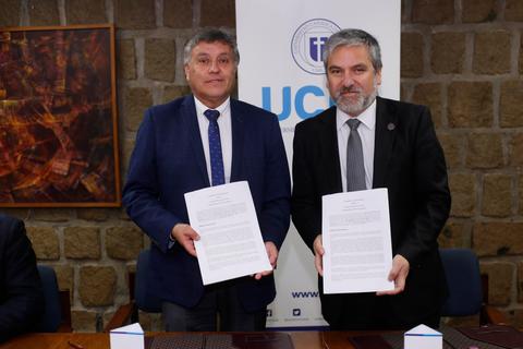 Dos hombres sostienen documentos en un ambiente formal.