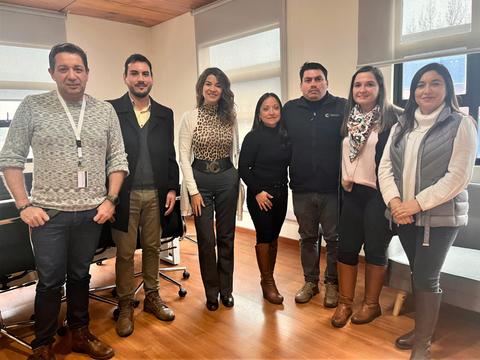 Un grupo de personas de pie en una oficina, sonriendo ante la cámara.