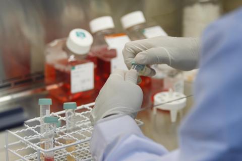 Un laboratorio de ciencias biológicas donde una persona manipula frascos de muestra en un ambiente controlado.