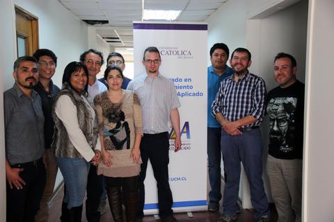 Un grupo de personas posando frente a un banner de la Universidad Católica de Chile.