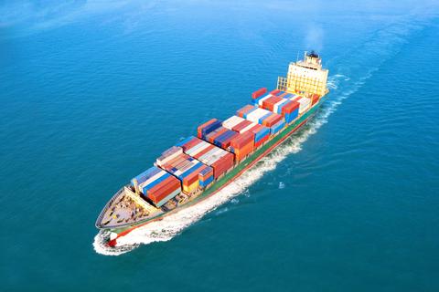 Un barco de carga navega a través del océano, llevando contenedores de colores distintos.