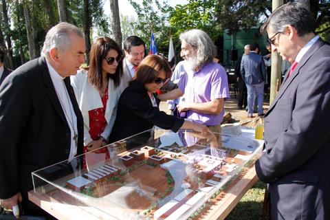 Un grupo de personas observa un modelo arquitectónico en un evento al aire libre.