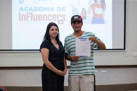 Un joven recibe un certificado de una mujer en un evento relacionado con influenciadores.