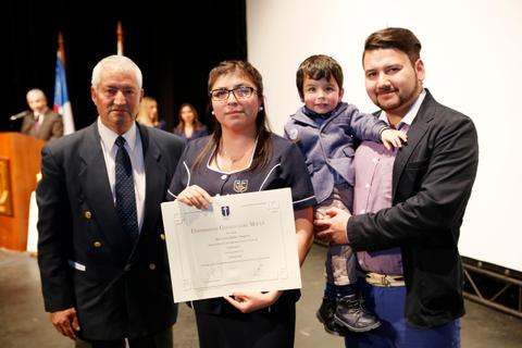 Una joven recibe un certificado en una ceremonia, acompañada de su familia.