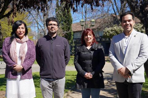 Cuatro personas posando al aire libre en un parque durante un día soleado.