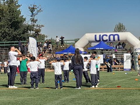 Un grupo de niños participa en actividades deportivas al aire libre bajo un cielo despejado.
