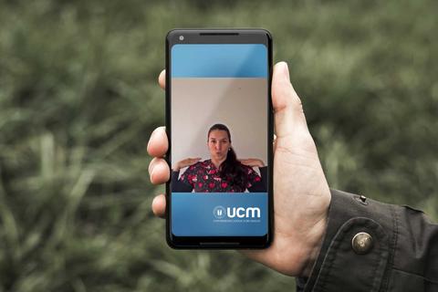 Una persona sostiene un teléfono móvil que muestra su propia imagen en una pantalla.