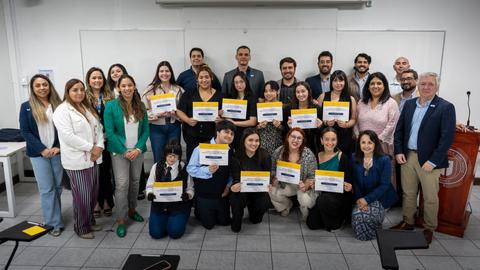 Un grupo de personas posando en un aula después de recibir certificados.