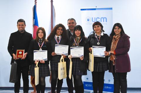 Un grupo de estudiantes sonrientes sostiene certificados y medallas en un evento de premiación.
