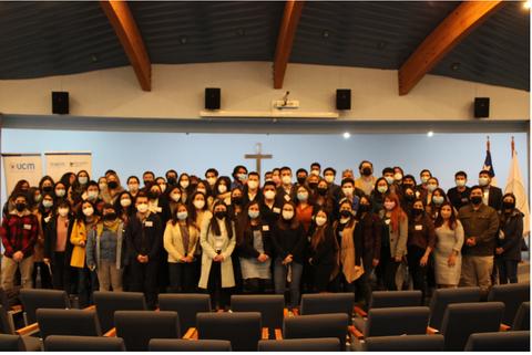 Un grupo numeroso de personas reunidas en un auditorio, la mayoría usando mascarillas.