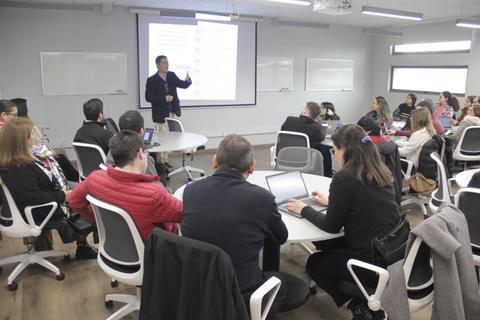 Un grupo de personas asiste a una presentación en un aula moderna.