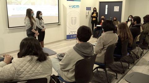 Dos presentadoras exponen en un evento educativo frente a una audiencia en un aula.