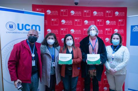 Un grupo de personas posando en un evento con carteles en las manos.
