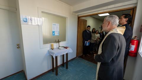 Una ceremonia de inauguración con un altar y personas observando.