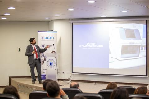 Un presentador explica el funcionamiento de un robot extractor de ADN durante una conferencia.