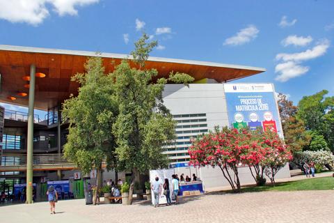 Una vista exterior de un edificio moderno con un cartel de inscripción y un ambiente soleado.