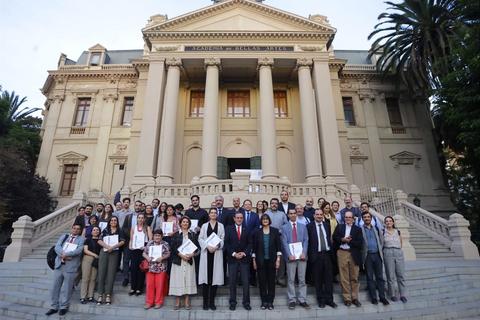 Un grupo de personas posando en las escaleras de un edificio imponente con columnas.