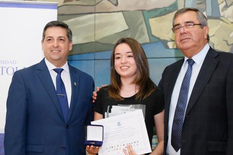 Una joven recibe un reconocimiento de dos hombres en un evento formal.