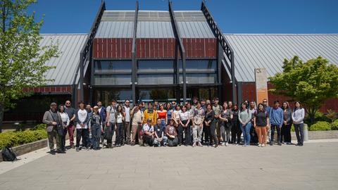 Un grupo de personas posando frente a un edificio moderno en un día soleado.