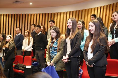 Grupo de personas de pie en un auditorio durante un evento.