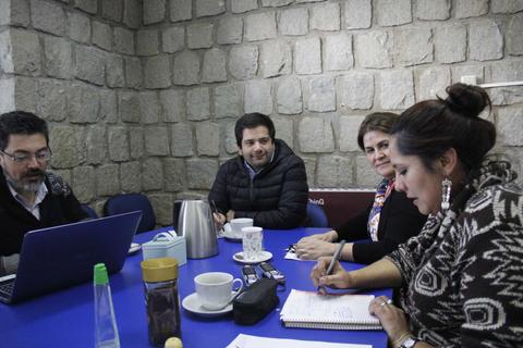 Un grupo de personas se encuentra reunido en una mesa, trabajando y tomando notas.